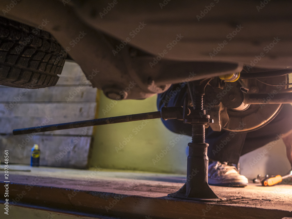 engineer rapairing car in garage using jack under it engineer rapairing car in garage using jack under it