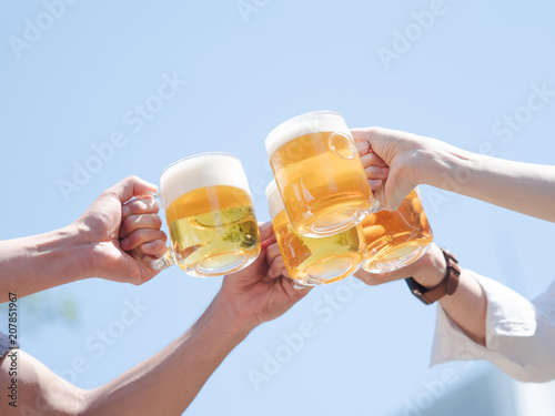 青空の下でビールで乾杯する男女4人の手元