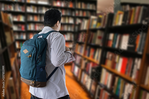 Happy Student with backpack go to holding books library bookshelves