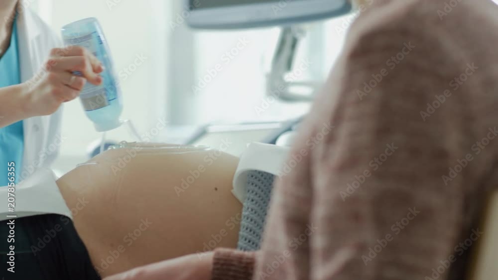 In the Hospital, Female Obstetrician Puts Gel on the Belly of a Pregnant Mother, Ready to do Ultrasound Screening. Shot on RED EPIC-W 8K Helium Cinema Camera. In the Hospital, Female Obstetrician Puts Gel on the Belly of a Pregnant Mother, Ready to do Ultrasound Screening. Shot on RED EPIC-W 8K Helium Cinema Camera.