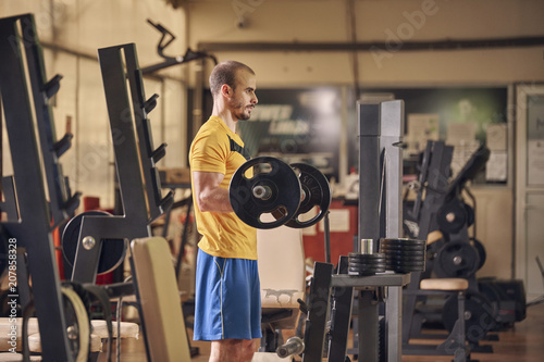 one young man, weight exercise, gym indoors exercise equipemnt, holding heavy weight bar.