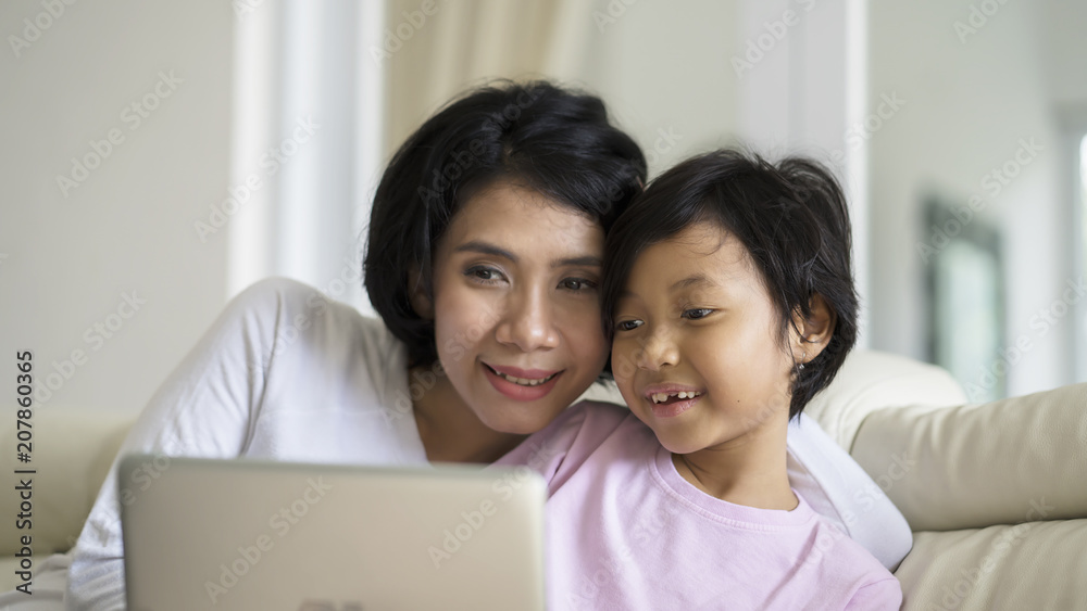Mother teaching her daughter to use a laptop Mother teaching her daughter to use a laptop