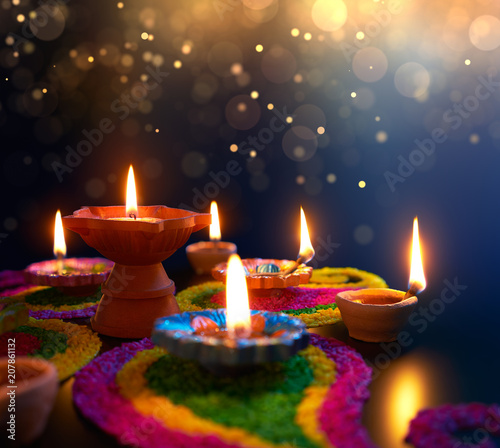 Diya lamps lit on colorful rangoli during diwali celebration