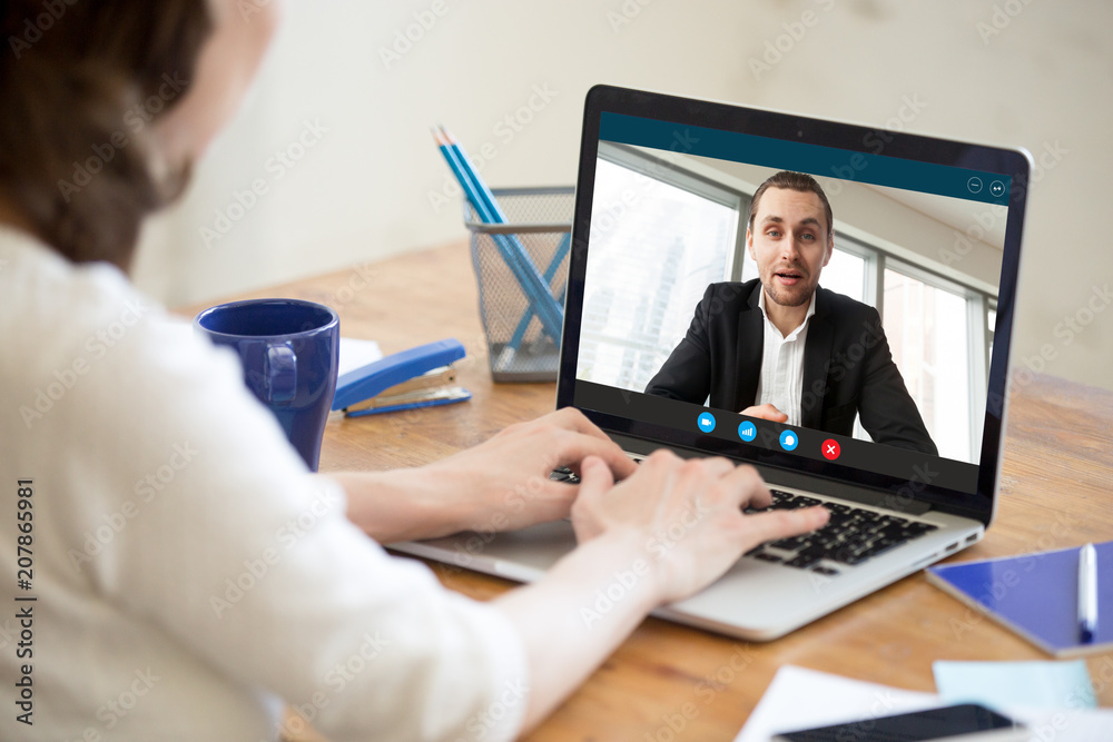 Businesswoman making video call to business partner using laptop. Close-up rear view of young woman having discussion with corporate client. Remote job interview, consultation, online meeting concept. Businesswoman making video call to business partner using laptop. Close-up rear view of young woman having discussion with corporate client. Remote job interview, consultation, online meeting concept.