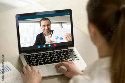 Happy businessman showing positive financial report to remote colleague via video conference call. Project manager proudly shows successful results over webcam application. Closeup view over shoulder.