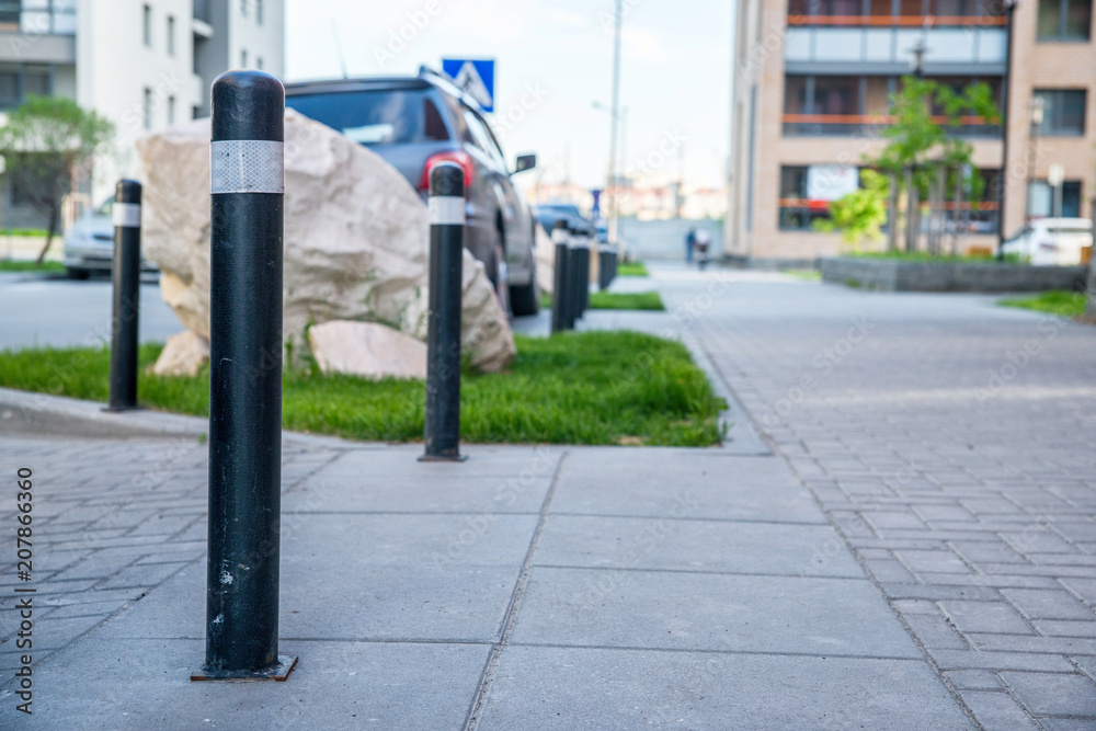 Obraz premium Bollards separating the roadway from the sidewalk in a residential area.