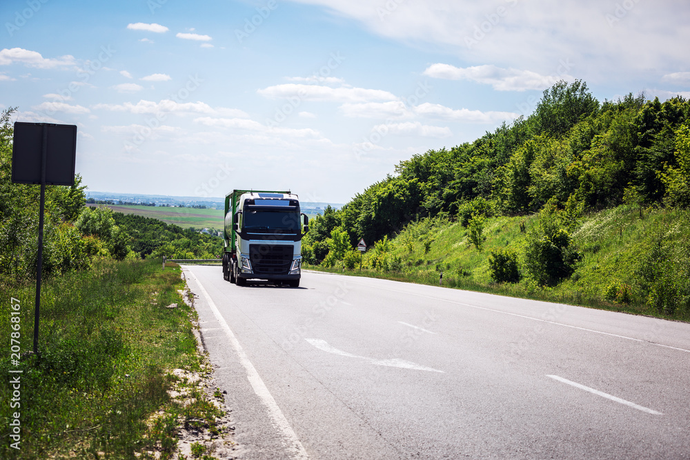 Arriving white truck on the road in a rural landscape at sunset