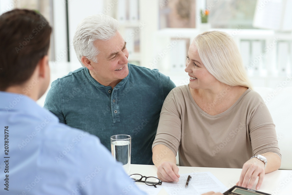 Mature couple discussing pension with consultant in office