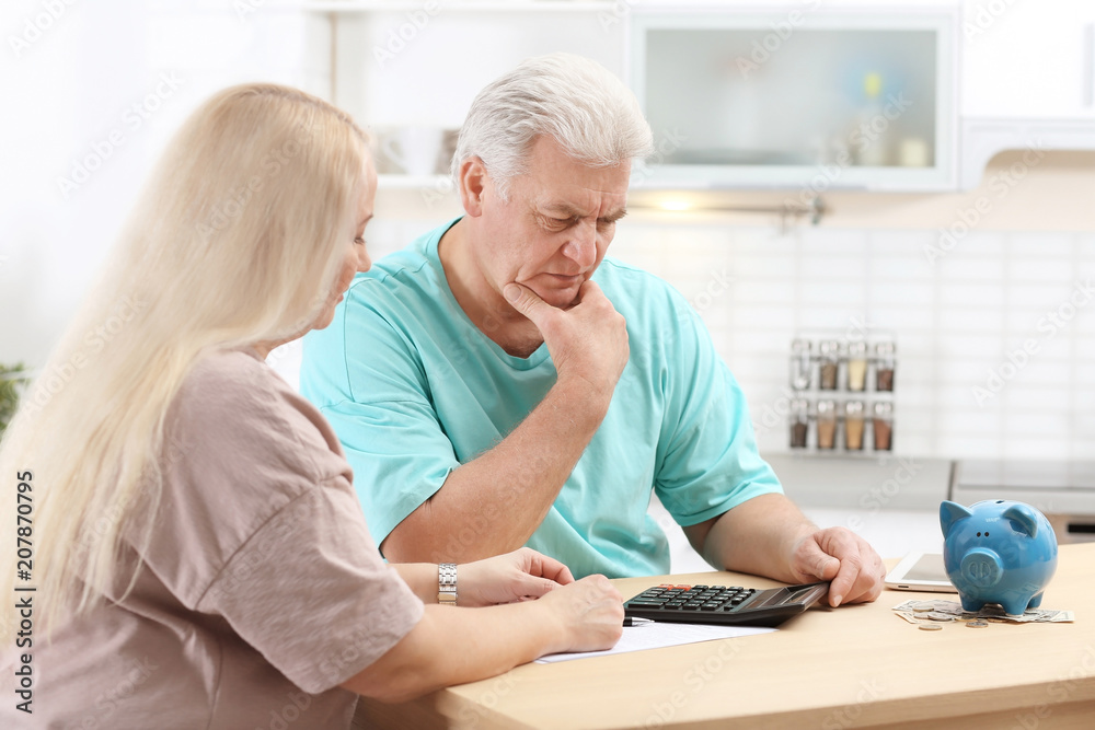 Mature couple thinking over pension payment at home Mature couple thinking over pension payment at home