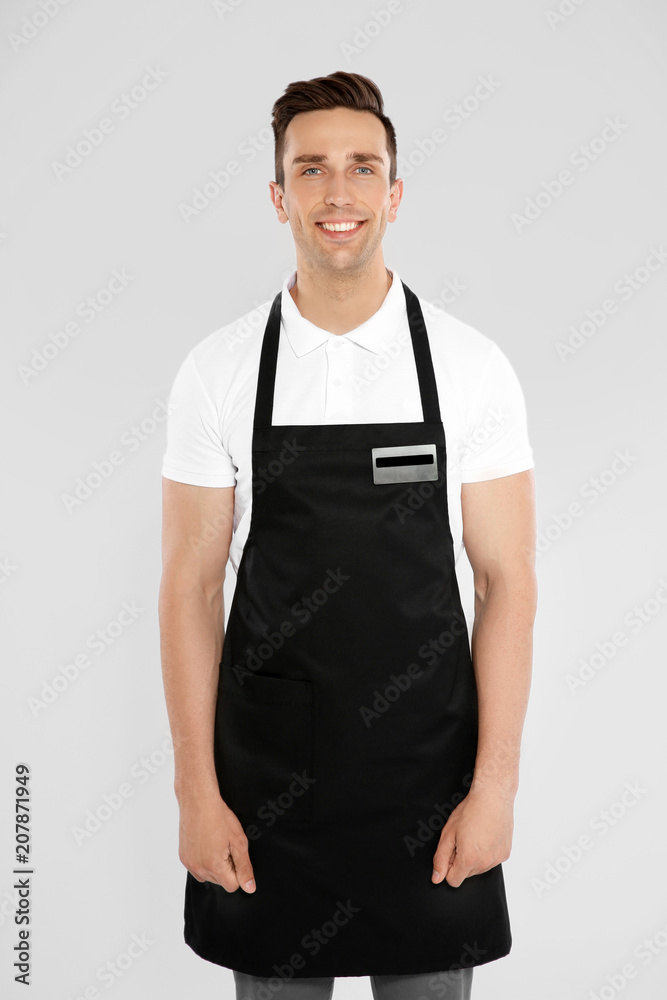 Portrait of handsome waiter in apron on light background Portrait of handsome waiter in apron on light background