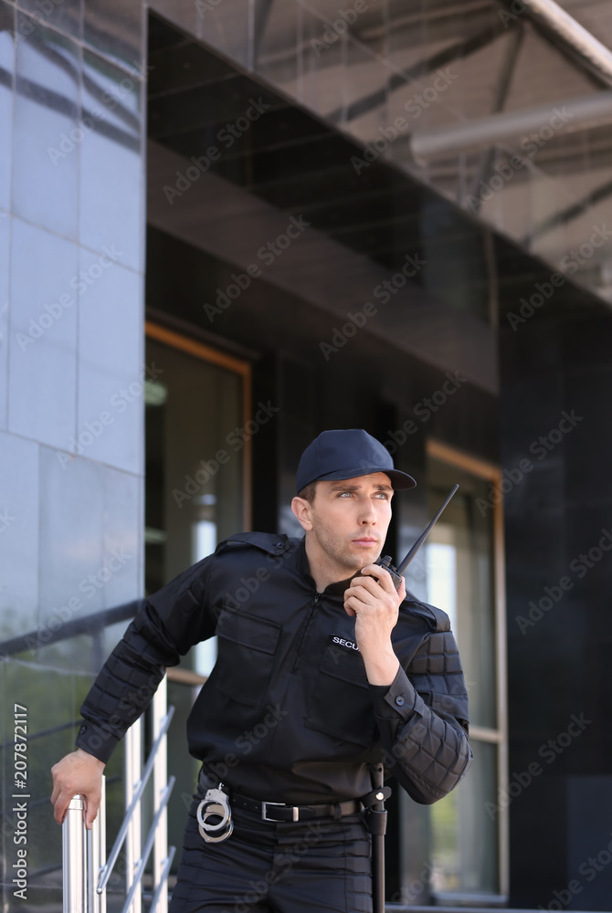 Male security guard using portable radio transmitter outdoors Male security guard using portable radio transmitter outdoors