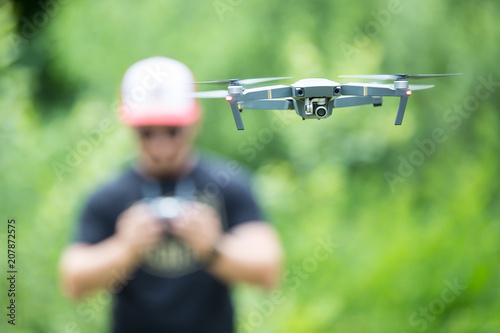 Young man holding remote controller and flying with drone in the park