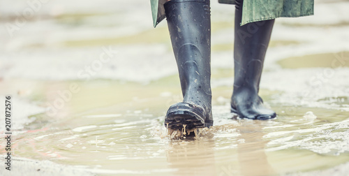 A man with black boots walks on a flooded road