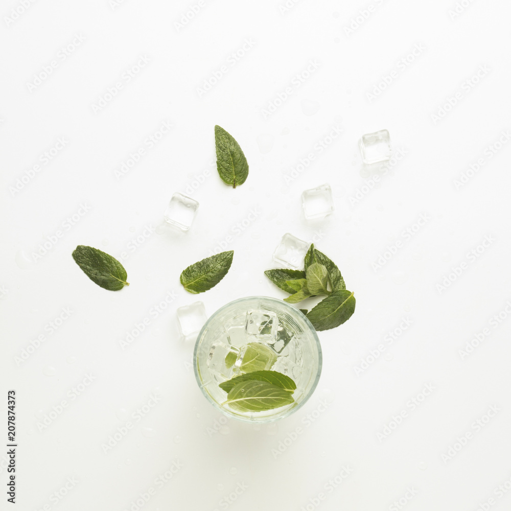 Obraz premium Glass with a refreshing drink with mint and ice on a light background. Flat lay, top view