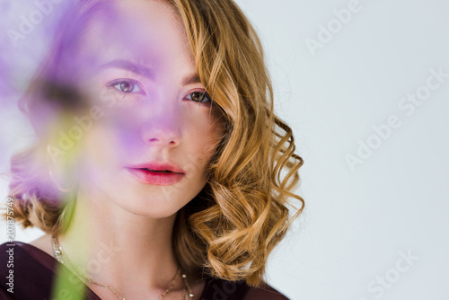 selective focus of beautiful young woman looking at camera isolated on grey