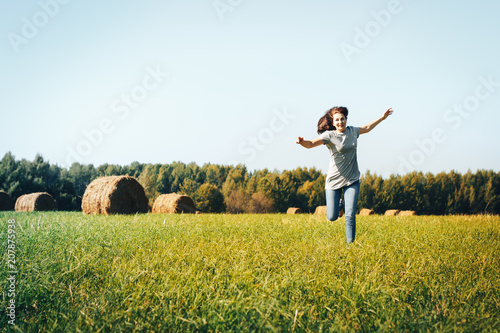 Girl in an autumn field with hay stack