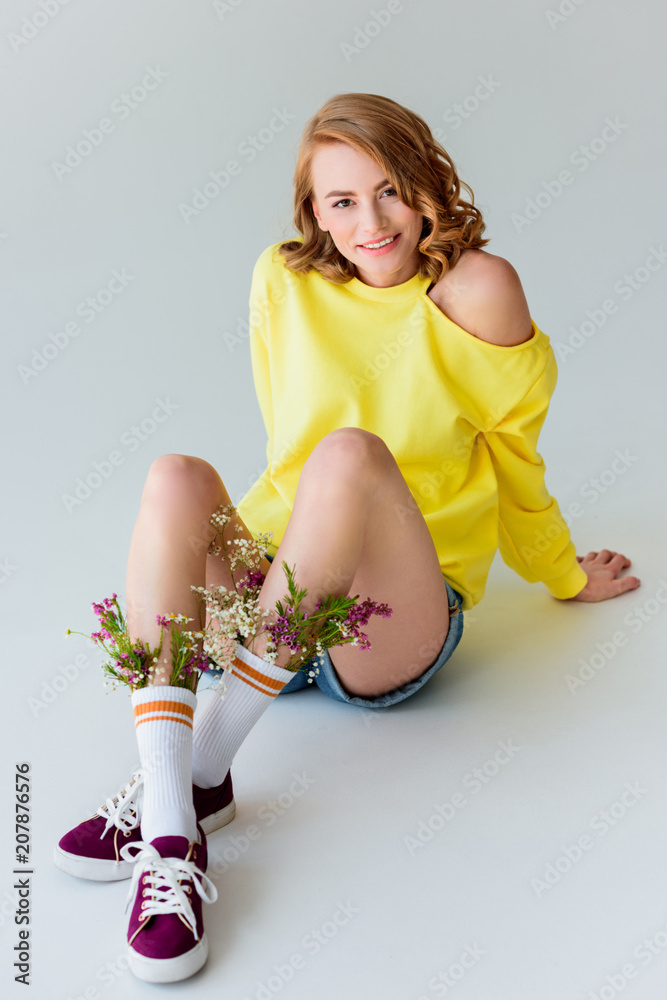 beautiful girl with flowers in socks sitting and smiling at camera isolated  on grey Stock Photo | Adobe Stock