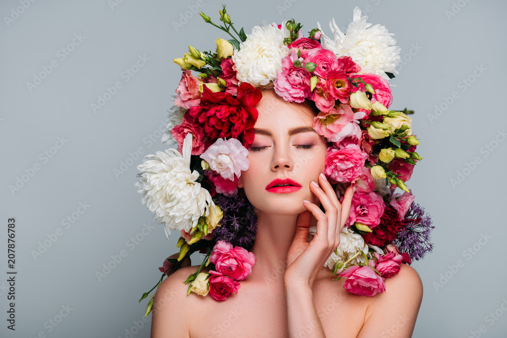 portrait of beautiful naked woman with closed eyes posing in floral wreath isolated on grey
