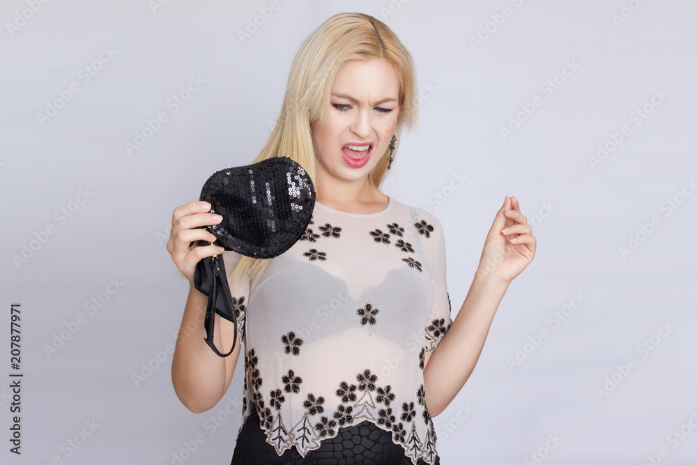 Fototapeta premium studio portrait of a young blond woman with long hair. Holds a shiny black heart shaped bag