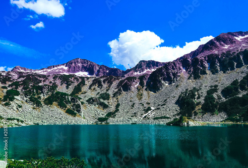 Beautiful alpine lake, river in the high mountains peak, blue sky background. Amazing Mountain hiking paradise landscape, summertime.