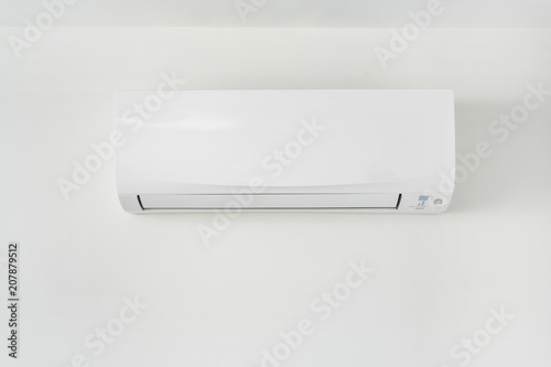 Air conditioner on white wall in area of room space.