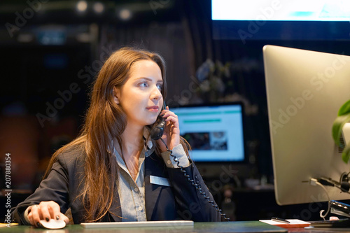 Hotel administrator. A woman-reception worker accepts an order for booking a room by phone. Profile shot of attractive executives at the reception of a hotel. The concept of service. photo