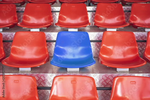 Red plastic chairs with blue seats in the middle.Concept the courage to be different.