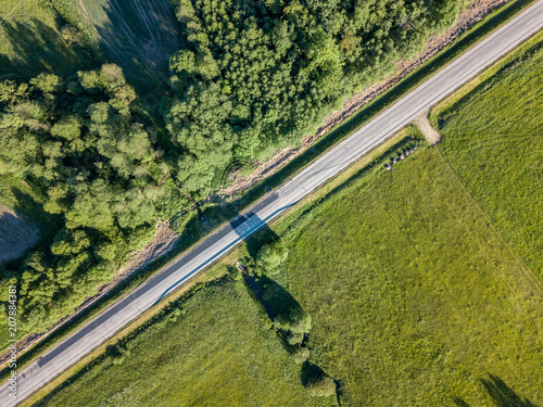 drone image. asphalt road surrounded by pine forest and fields from above