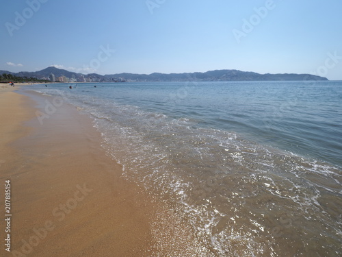 Sandy beach at bay of ACAPULCO city in Mexico with holiday panoramic view and waves of Pacific Ocean