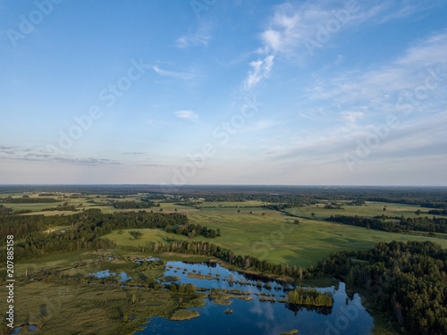 drone image. country lake surrounded by pine forest and fields from above
