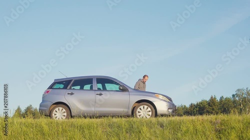 Man repairing a broken car by the road photo