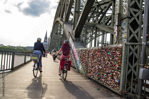 A couple on bicycles rides across the bridge to Cologne Cathedral