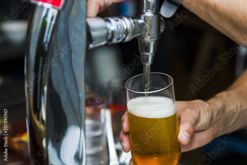 Bartender pouring fresh cold beer from tap