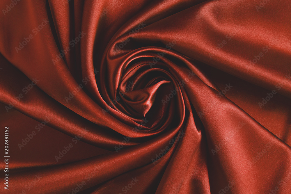 Obraz premium Close up of ripplesin shape of rose flower in red silk fabric. Satin textile background.