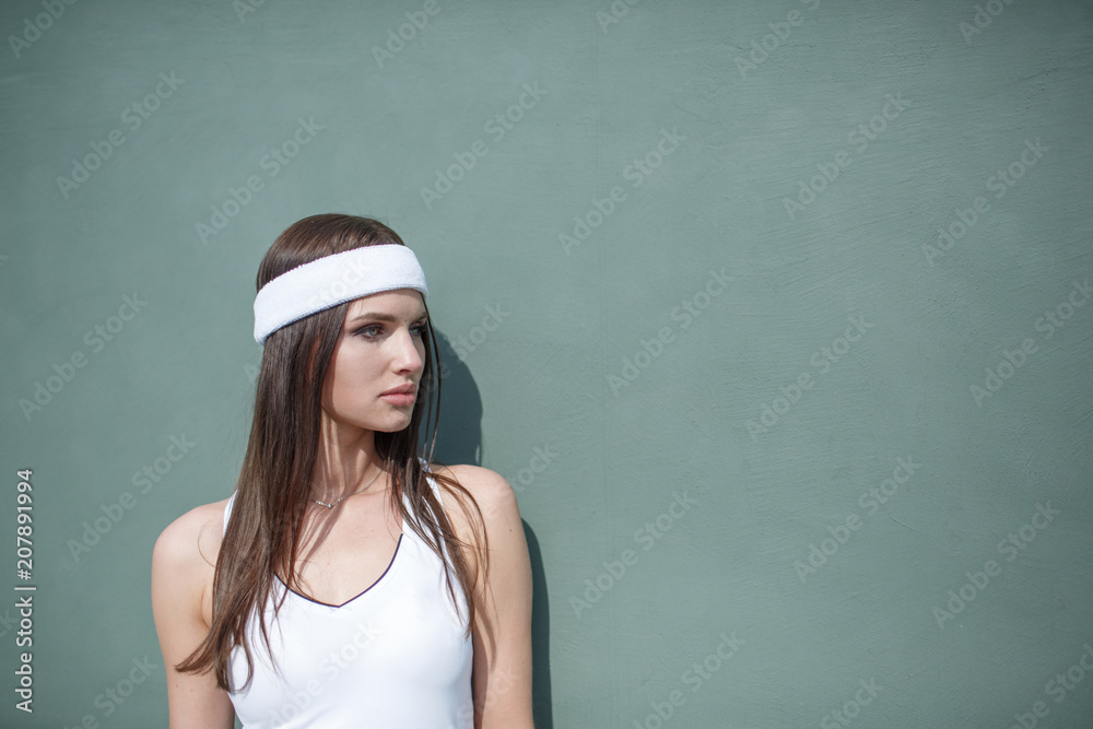 Portrait of young Caucasian teen model wearing fashionable tennis dress, posing on tennis hardcourt, summer sunny day outdoors. Fashion portrait shoot Portrait of young Caucasian teen model wearing fashionable tennis dress, posing on tennis hardcourt, summer sunny day outdoors. Fashion portrait shoot