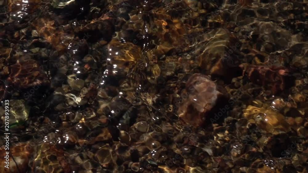 Slow motion of rapid water, flowing over brown and red boulders and pebbles. High speed camera shooting of ripple in mountain stream close up. Relax view for meditative intro. Natural beauty. Slow motion of rapid water, flowing over brown and red boulders and pebbles. High speed camera shooting of ripple in mountain stream close up. Relax view for meditative intro. Natural beauty.