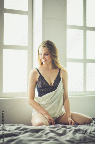 Portrait of beautiful young woman in nightwear on bed