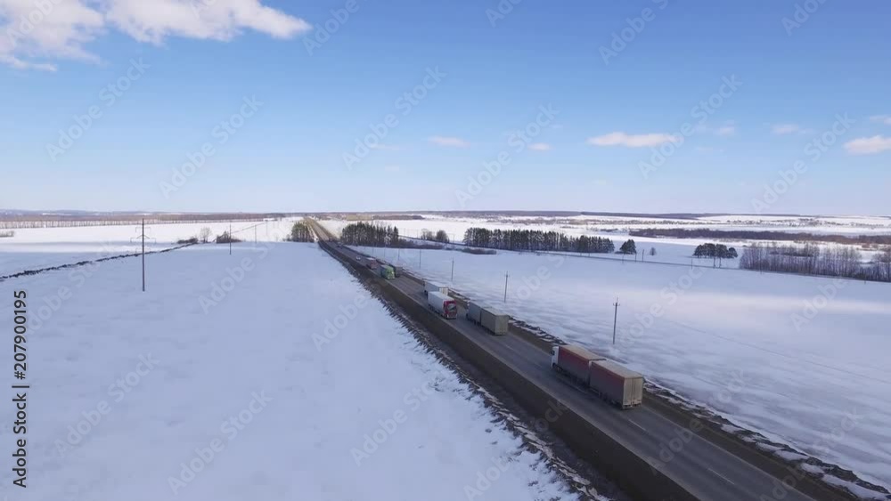 Aerial Photography - shot with drone camera. A Few truck driving on highway in russia at winter sunny day of partly cloudy sky. Aerial Photography - shot with drone camera. A Few truck driving on highway in russia at winter sunny day of partly cloudy sky.