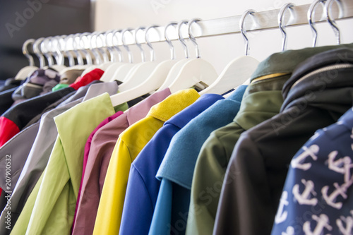 Colorful softshell coats on rack with hangers. Fashion conception.