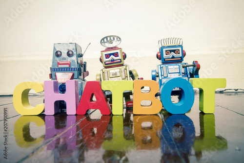 the word  CHAT BOT with wooden letters and retro toy robots  on an old wooden floor