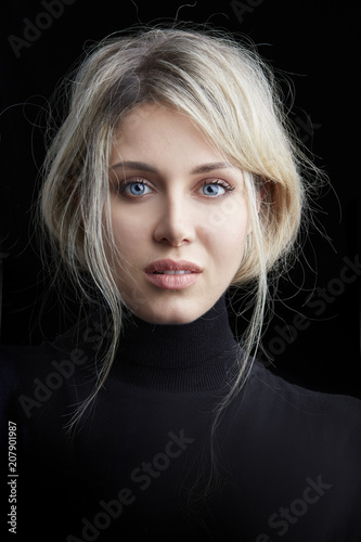 blonde woman with gathered hair and round necked black jumper on black background
