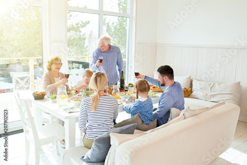 Canvastavla Wide angle portrait of happy two generation family enjoying dinner together sitt