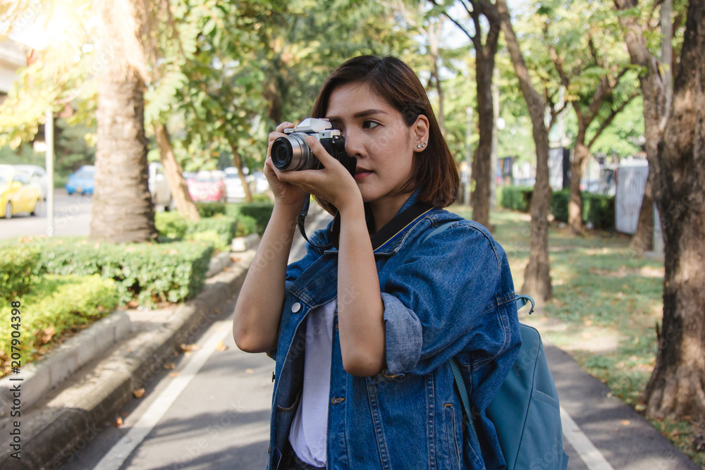 Happy beautiful traveler asian woman carry backpack. Young joyful asian women using camera to making photo during city tour, cheerful emotions, great mood. Women lifestyle outdoor in city concept.