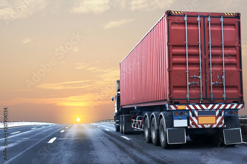 Truck on highway road with red container, transportation concept.,import,export logistic industrial Transporting Land transport on the asphalt expressway with sunrise sky