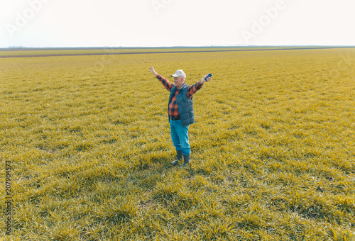 Senior farmer in wheat field with arms outstretched.