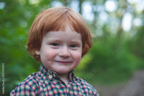 Red-haired boy in plaid shirt smiles
