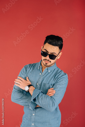 Smiling Asian businessman in glasses.The young man wears a stylish denim shirt on a red background