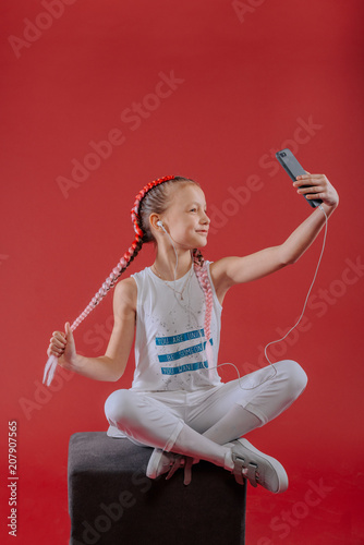 Adorable little girl taking a photo of herself with a smartphone
