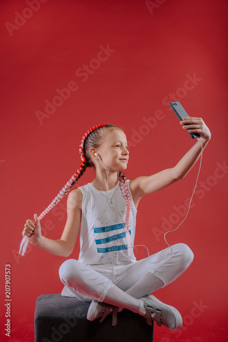 Adorable little girl taking a photo of herself with a smartphone.Beautiful little girl listening to music.The girl speaks to Skype with her friends