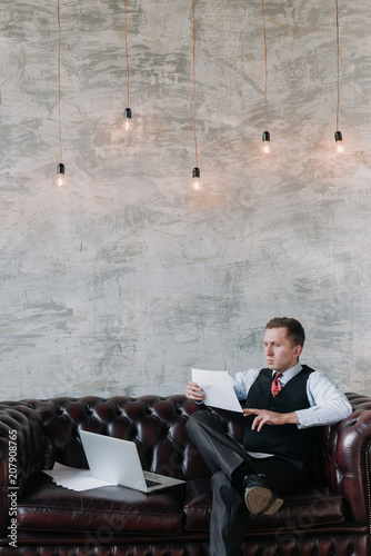 Serious self employed man working on the laptop.handsome man sitting on couch and using laptop